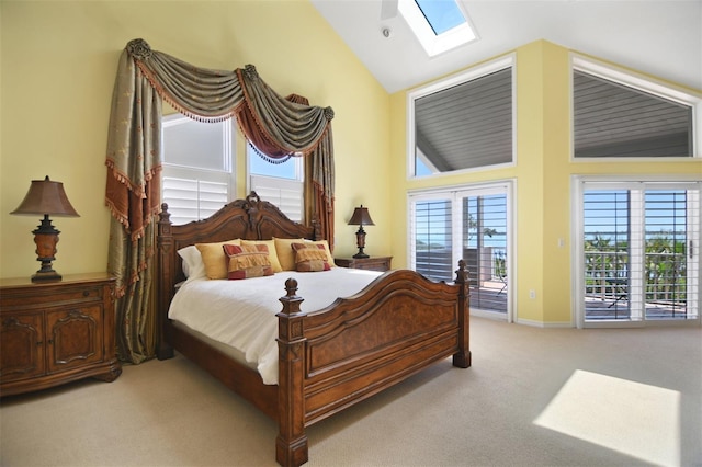 carpeted bedroom with vaulted ceiling with skylight, baseboards, multiple windows, and access to exterior