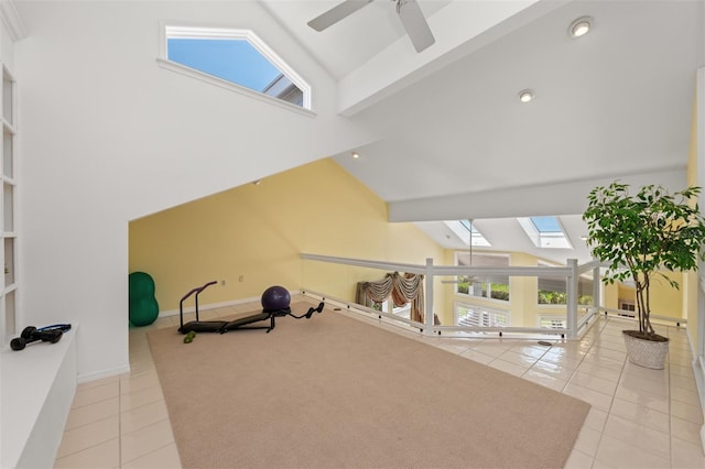 exercise area with a skylight, high vaulted ceiling, and tile patterned flooring