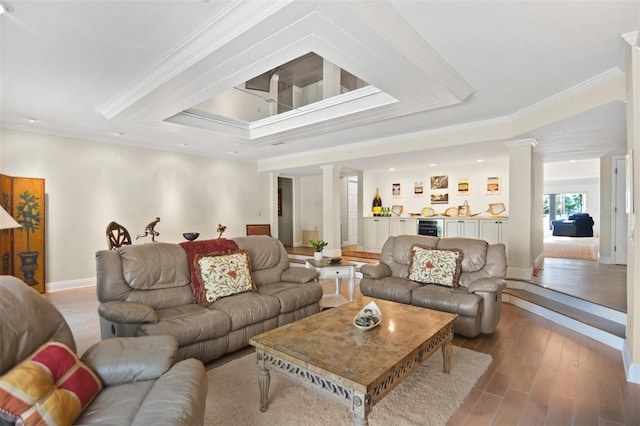 living area with baseboards, ornamental molding, decorative columns, and wood finished floors