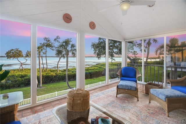 sunroom / solarium with a water view, tile patterned floors, vaulted ceiling, and floor to ceiling windows