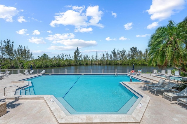 community pool featuring a water view, a patio area, and fence