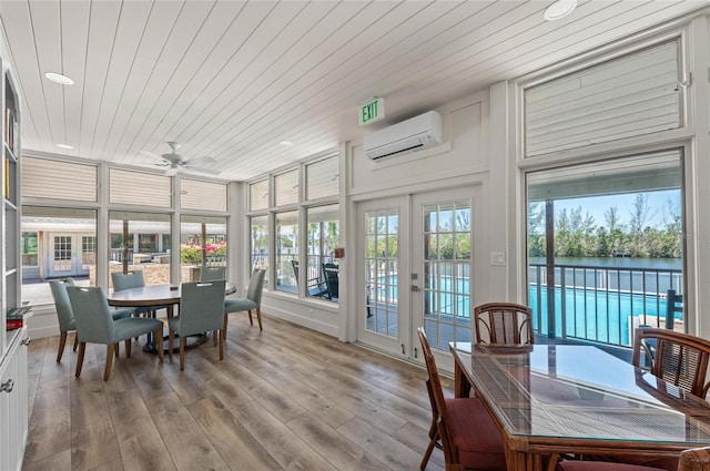 sunroom / solarium featuring wooden ceiling, a water view, a wall mounted AC, and french doors