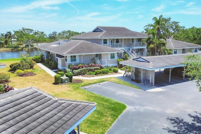 exterior space with a lawn, driveway, a water view, and a carport