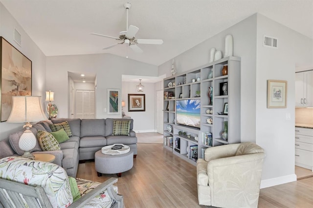 living room with lofted ceiling, visible vents, ceiling fan, and light wood-style flooring