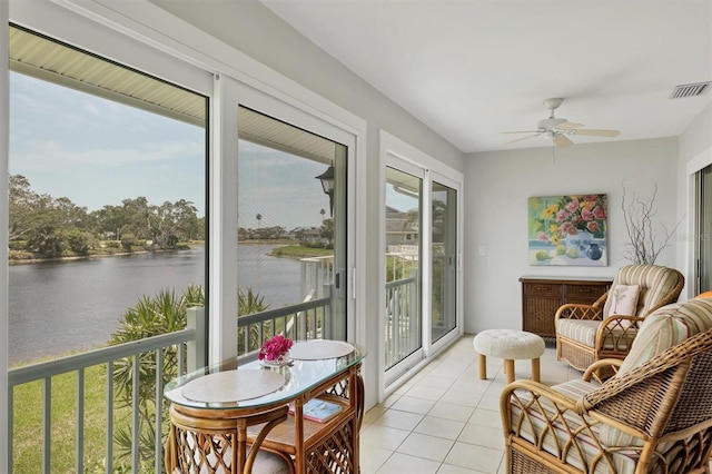 sunroom featuring tile patterned floors, visible vents, and a water view