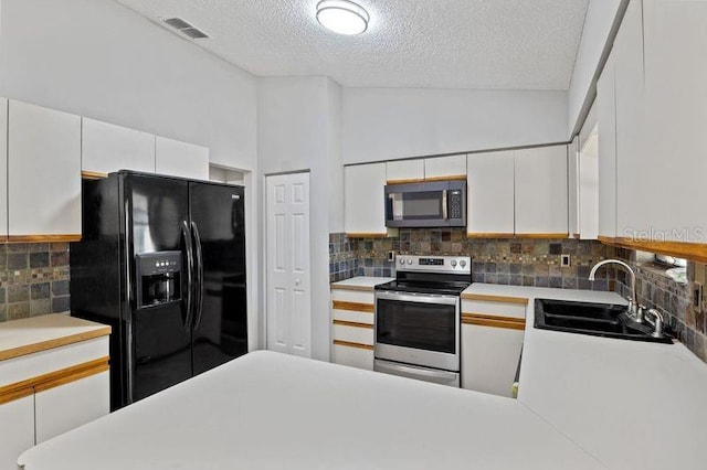 920 36th St W, Bradenton, FL 34205 - kitchen featuring stainless steel appliances, a sink, tasteful backsplash, a textured ceiling, and white cabinets