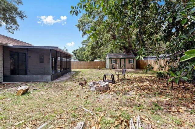 920 36th St W, Bradenton, FL 34205 - fenced backyard with a sunroom, a storage unit, an outdoor structure, and a fire pit