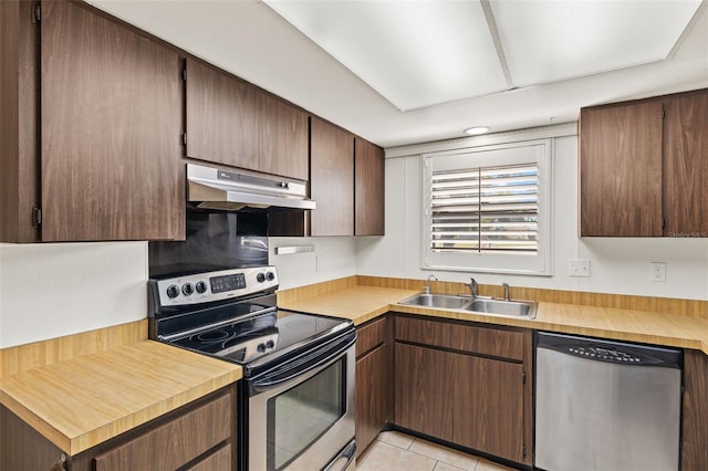6547 Samoa Dr, Sarasota, FL 34241 - kitchen with appliances with stainless steel finishes, under cabinet range hood, a sink, light tile patterned floors, and light countertops