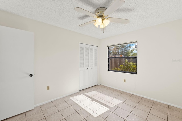 6547 Samoa Dr, Sarasota, FL 34241 - unfurnished bedroom with a textured ceiling, light tile patterned floors, a closet, baseboards, and a ceiling fan