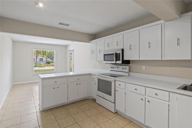 3505 27th Ave W, Bradenton, FL 34205 - kitchen with stainless steel microwave, white electric range oven, a peninsula, light tile patterned floors, and light countertops