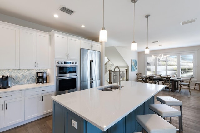 222 Willow Ave, Anna Maria, FL 34216 - kitchen with appliances with stainless steel finishes, a sink, white cabinetry, backsplash, and visible vents