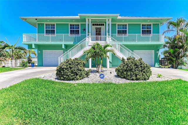 raised beach house featuring covered porch, an attached garage, and stairway