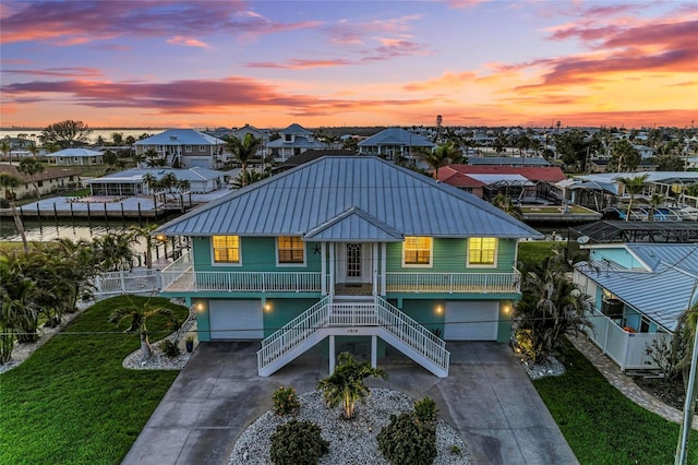 coastal inspired home featuring concrete driveway, an attached garage, metal roof, and stairs
