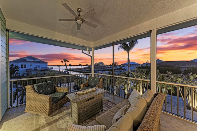 balcony with a water view, ceiling fan, and outdoor lounge area