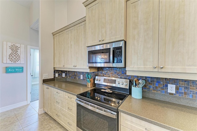 kitchen with dark countertops, appliances with stainless steel finishes, tasteful backsplash, and light tile patterned flooring