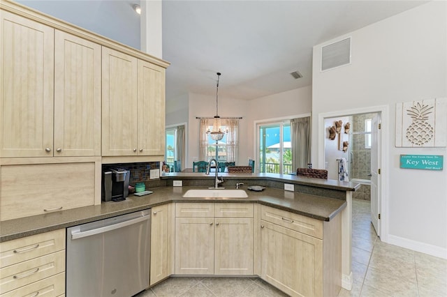 kitchen featuring light brown cabinetry, a peninsula, a sink, and dishwasher