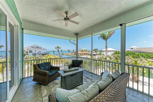 sunroom / solarium with an outdoor living space, a water view, and ceiling fan
