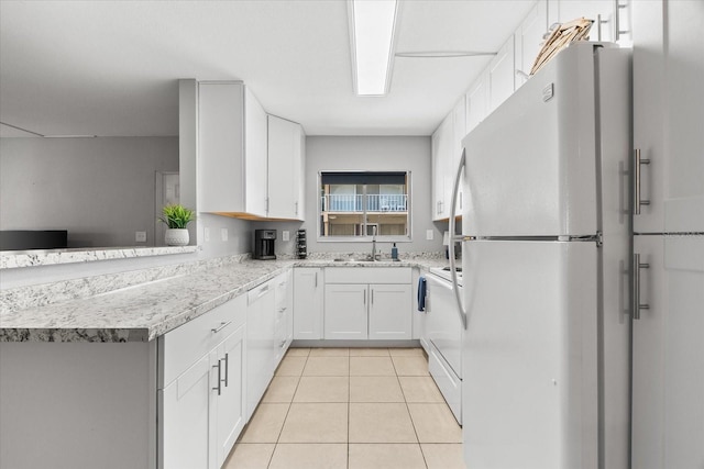 kitchen with white appliances, light stone countertops, white cabinets, a sink, and light tile patterned floors