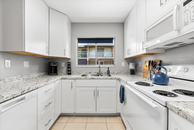 kitchen featuring white appliances, white cabinetry, light stone counters, a sink, and light tile patterned floors