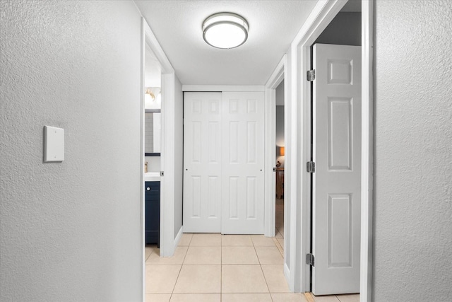 hallway with a textured wall and light tile patterned floors