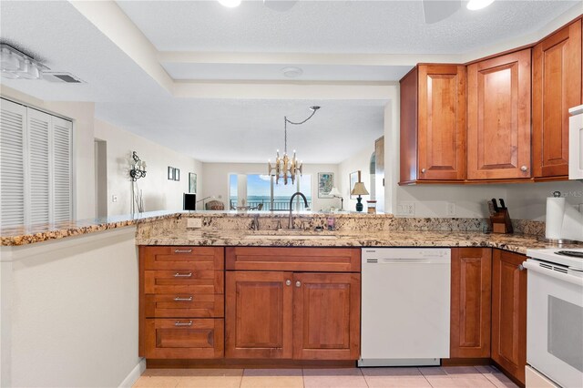 6460 Mourning Dove Dr Unit 102, Bradenton, FL 34210 - kitchen with white appliances, a sink, brown cabinets, light stone countertops, and a peninsula