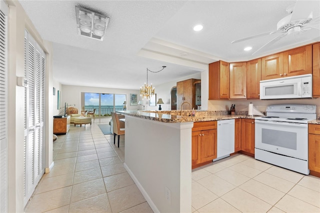6460 Mourning Dove Dr Unit 102, Bradenton, FL 34210 - kitchen featuring white appliances, open floor plan, a peninsula, light tile patterned floors, and light stone countertops