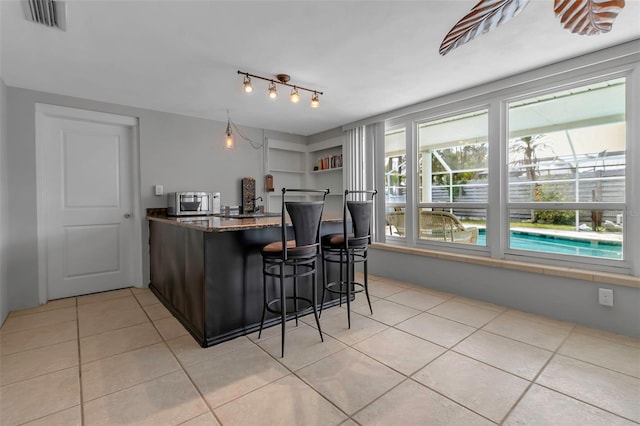 6422 Beechwood Ave, Sarasota, FL 34231 - kitchen with stainless steel microwave, dark stone countertops, visible vents, and light tile patterned floors