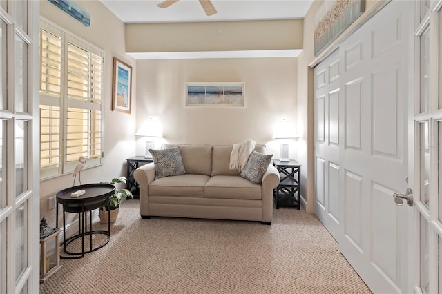 living area featuring carpet, plenty of natural light, and a ceiling fan