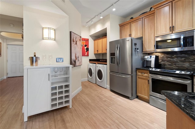 kitchen with tasteful backsplash, light wood-style floors, stainless steel appliances, washer and dryer, and track lighting