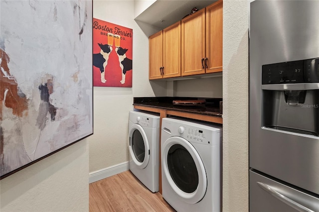 laundry area featuring baseboards, light wood-style flooring, laundry area, and washer and clothes dryer