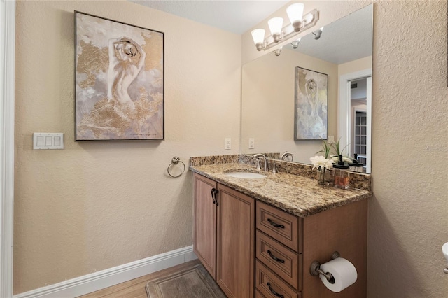 bathroom with wood finished floors, vanity, and baseboards