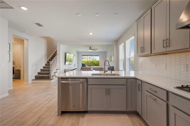 kitchen with wall chimney exhaust hood, dishwasher, gray cabinetry, and a sink