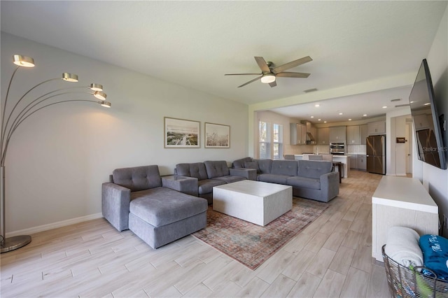 living room featuring light wood-style flooring, visible vents, baseboards, and ceiling fan