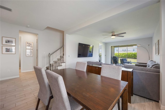 dining area with stairs, ceiling fan, light wood finished floors, baseboards, and visible vents