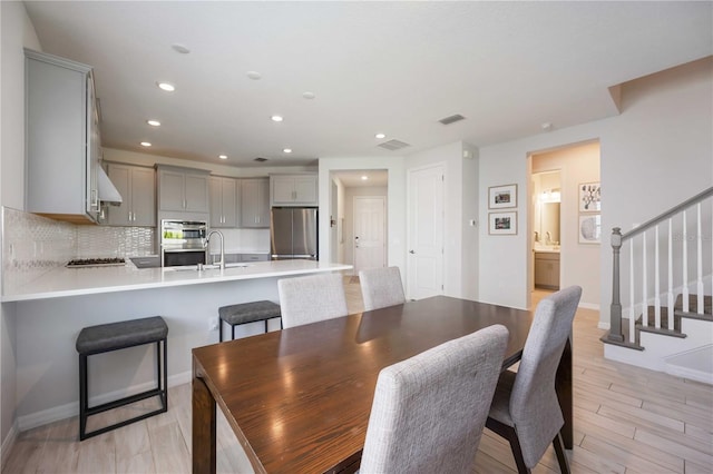 dining room with stairway, light wood-style floors, baseboards, visible vents, and recessed lighting