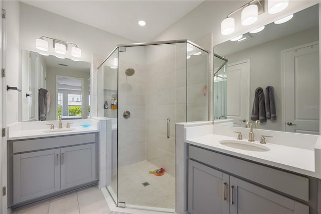 bathroom featuring two vanities, tile patterned flooring, a stall shower, and a sink