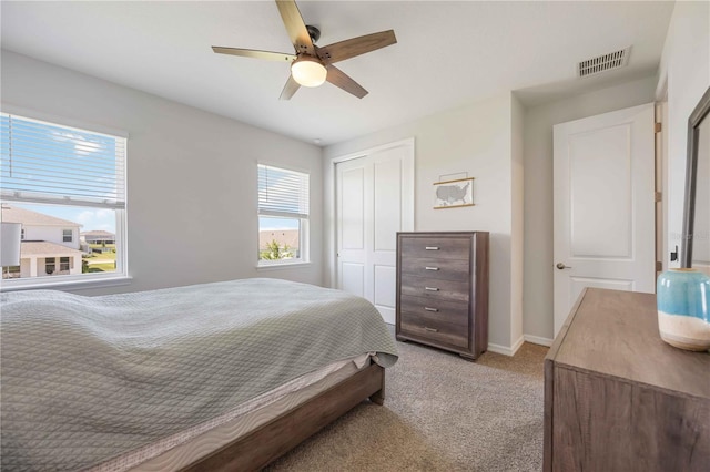bedroom with a closet, ceiling fan, light colored carpet, baseboards, and visible vents