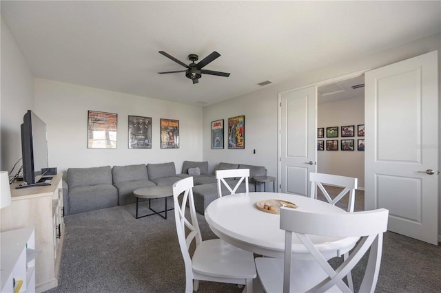 dining space with dark colored carpet, visible vents, and ceiling fan