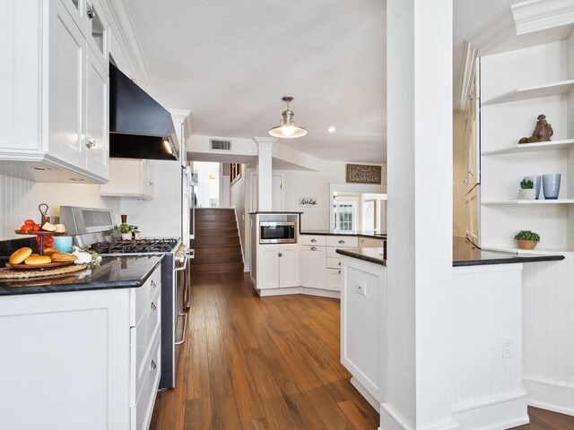 8871 Fishermens Bay Dr, Sarasota, FL 34231 - kitchen with dark countertops, visible vents, stainless steel appliances, wall chimney exhaust hood, and decorative columns