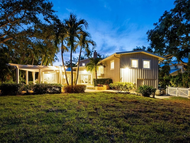 8871 Fishermens Bay Dr, Sarasota, FL 34231 - view of front of home featuring fence, a chimney, board and batten siding, and a front lawn
