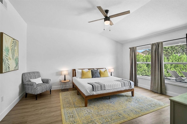 bedroom featuring lofted ceiling, baseboards, wood finished floors, and a ceiling fan
