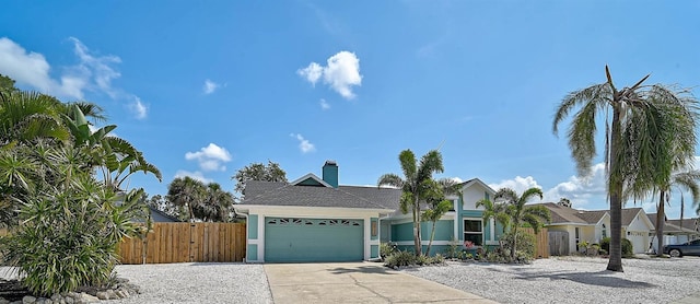 view of front of home with fence, an attached garage, concrete driveway, and a chimney