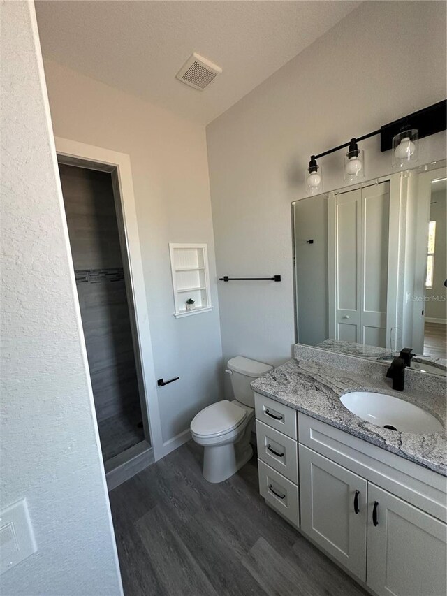 14343 Myakka Ave, Port Charlotte, FL 33953 - bathroom with wood finished floors, toilet, vanity, baseboards, and visible vents