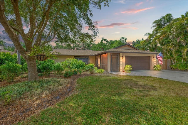 single story home with an attached garage, stucco siding, a yard, and driveway