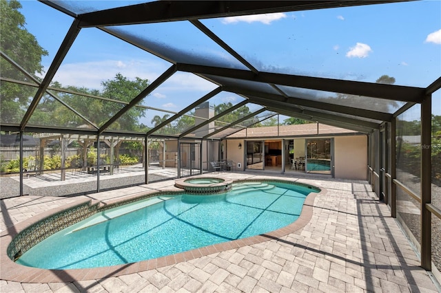 view of swimming pool featuring a lanai, a pool with connected hot tub, and a patio area