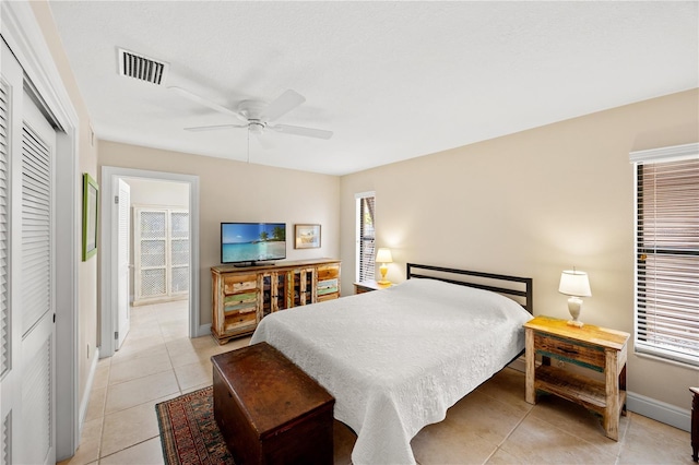 bedroom with visible vents, a closet, baseboards, a ceiling fan, and light tile patterned floors