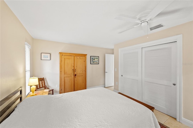 bedroom featuring light tile patterned floors, ceiling fan, baseboards, and a closet