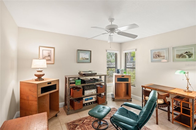 living area with light tile patterned floors, baseboards, and a ceiling fan