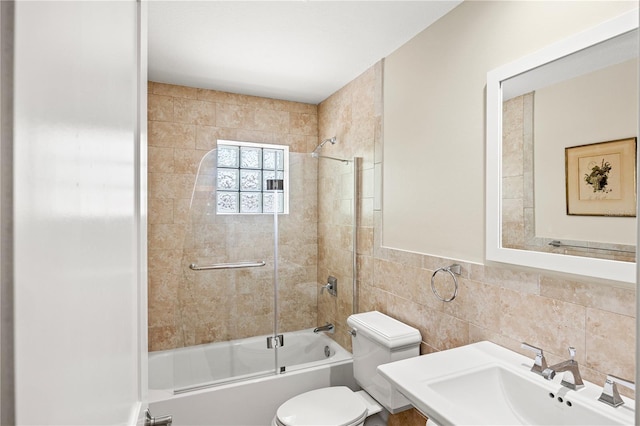 full bathroom with toilet, tile walls, shower / tub combination, and a sink