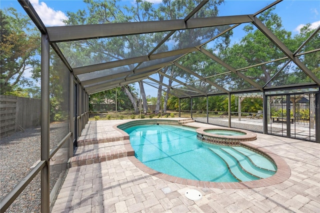 view of pool with a lanai, a patio area, a pool with connected hot tub, and fence
